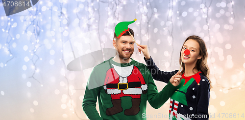 Image of couple with christmas party props in ugly sweaters