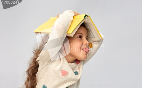 Image of portrait of smiling girl with book on head