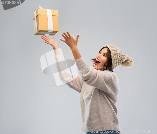 Image of young woman in winter hat catching gift box