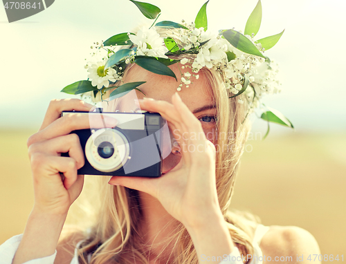 Image of happy woman with film camera in wreath of flowers