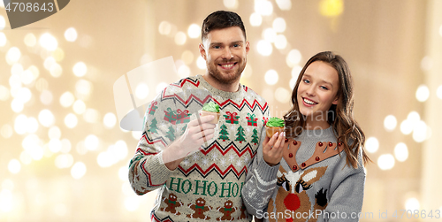 Image of couple with cupcakes in ugly christmas sweaters