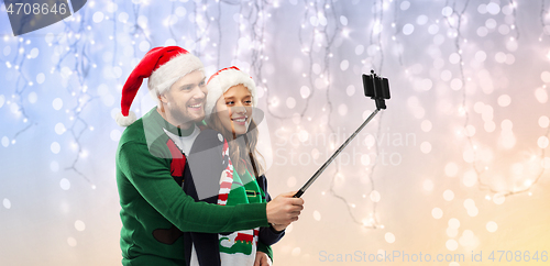 Image of happy couple in christmas sweaters taking selfie