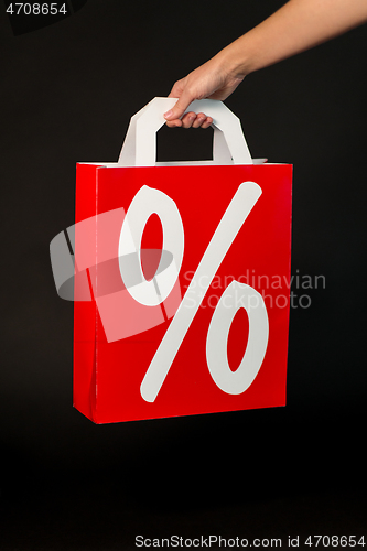 Image of hand holding red shopping bag with percent sign