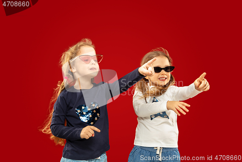 Image of Beautiful emotional little girls isolated on red background