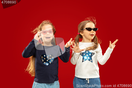 Image of Beautiful emotional little girls isolated on red background