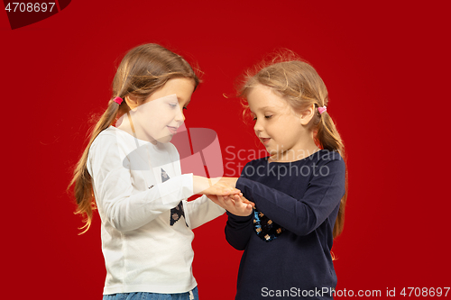 Image of Beautiful emotional little girls isolated on red background