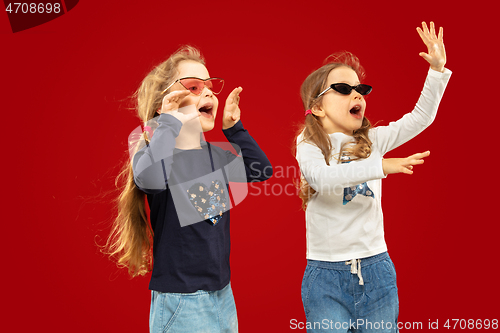 Image of Beautiful emotional little girls isolated on red background