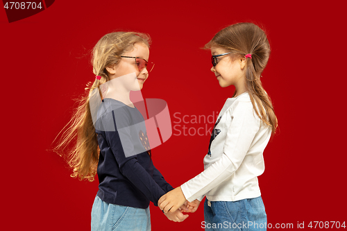 Image of Beautiful emotional little girls isolated on red background