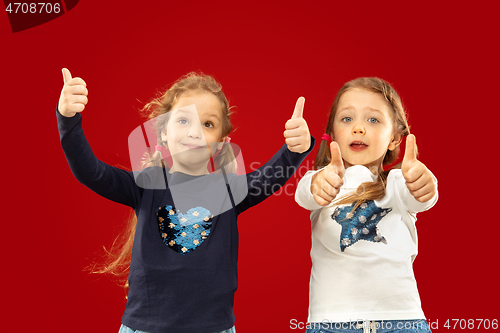 Image of Beautiful emotional little girls isolated on red background