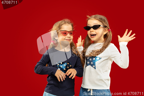 Image of Beautiful emotional little girls isolated on red background