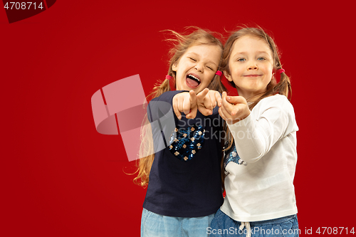 Image of Beautiful emotional little girls isolated on red background