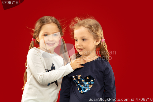 Image of Beautiful emotional little girls isolated on red background