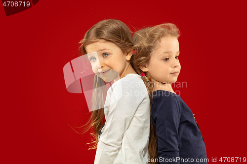 Image of Beautiful emotional little girls isolated on red background