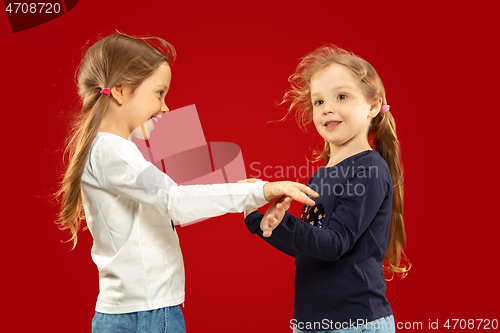 Image of Beautiful emotional little girls isolated on red background