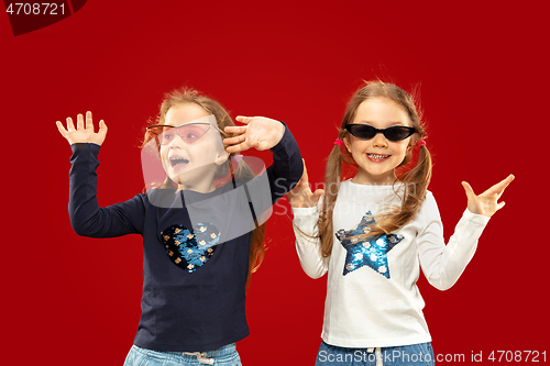 Image of Beautiful emotional little girls isolated on red background