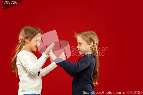 Image of Beautiful emotional little girls isolated on red background