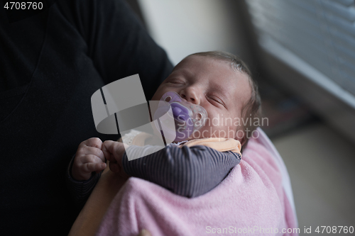 Image of grandmother holding newborn baby at home