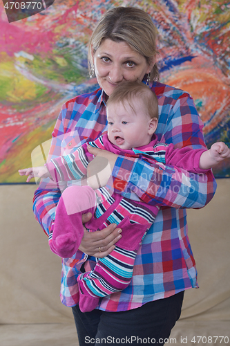 Image of grandmother holding newborn baby at home