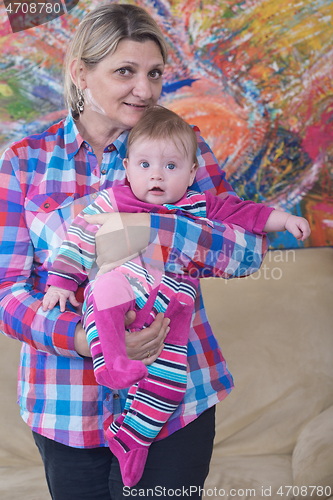 Image of grandmother holding newborn baby at home