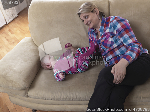 Image of grandmother is playing with newborn baby