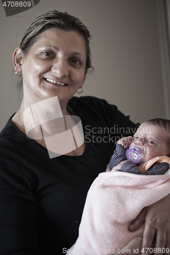 Image of grandmother holding newborn baby at home