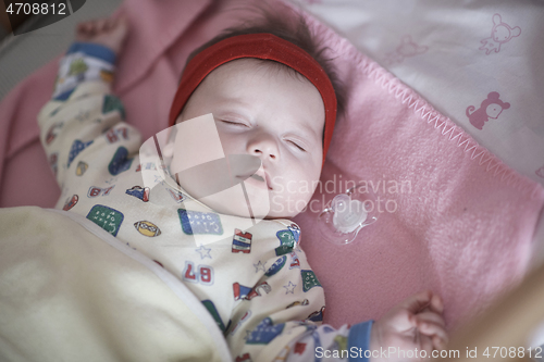 Image of newborn baby sleeping at home in bed