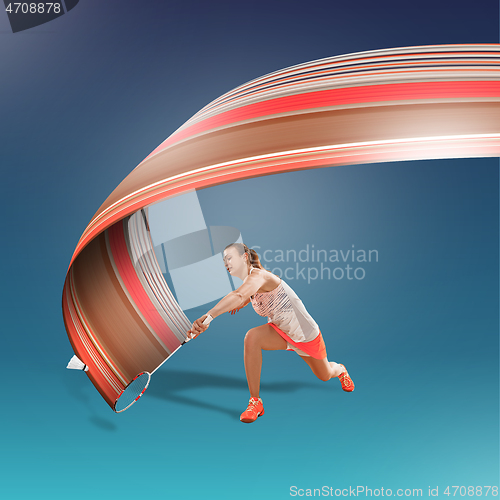 Image of Full length portrait of young woman playing badminton isolated on blue background
