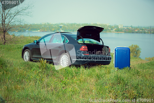 Image of View of modern black car and suitcase on the river\'s side