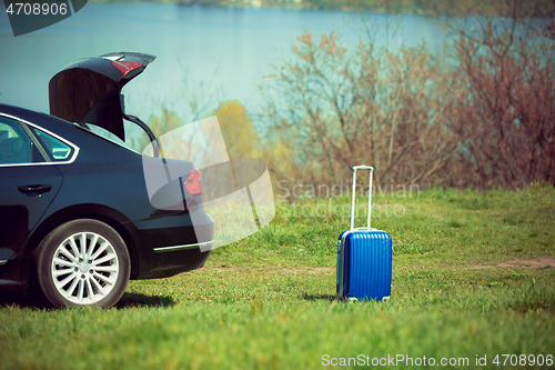 Image of View of modern black car and suitcase on the river\'s side