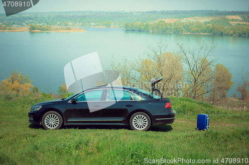 Image of View of modern black car and suitcase on the river\'s side