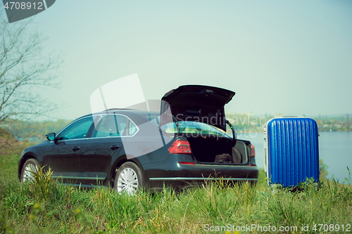 Image of View of modern black car and suitcase on the river\'s side