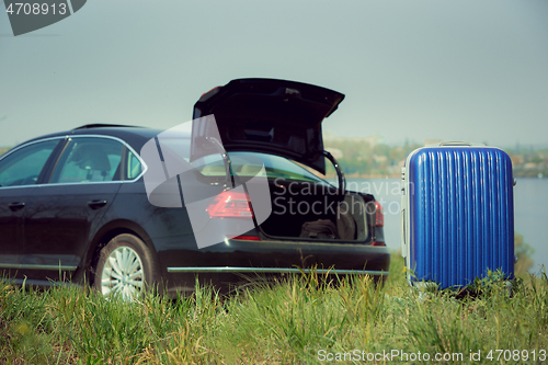 Image of View of modern black car and suitcase on the river\'s side