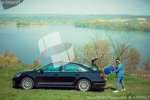 Image of Handsome smiling man sitting in his car with opened doors