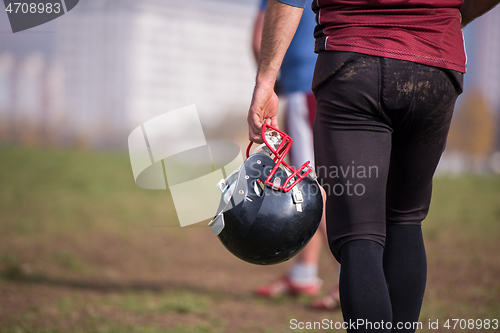 Image of American football player holding helmet