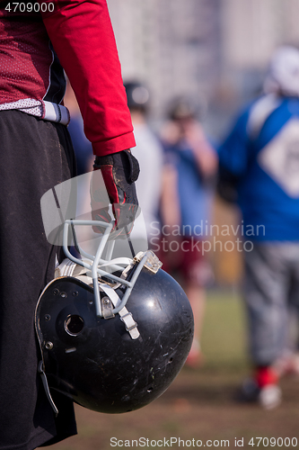 Image of American football player holding helmet