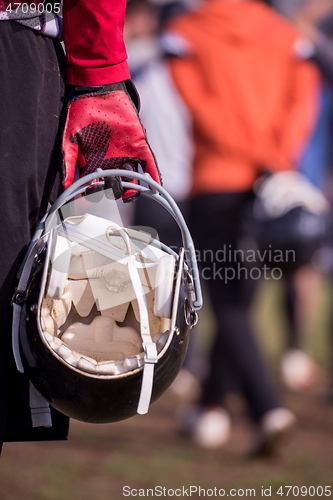 Image of American football player holding helmet