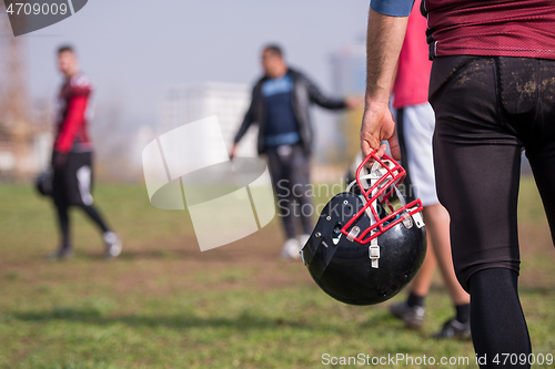 Image of American football player holding helmet