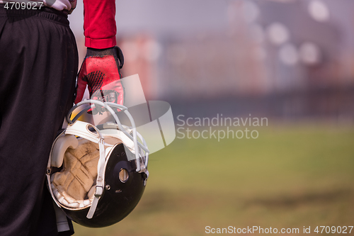 Image of American football player holding helmet