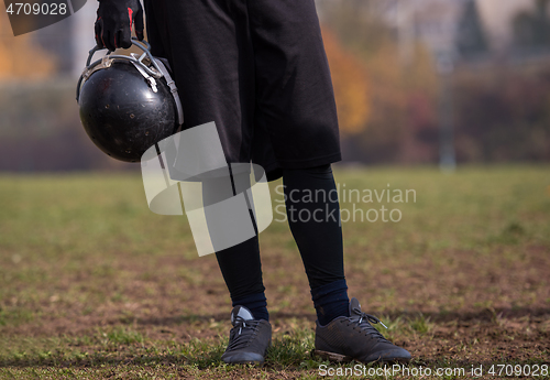 Image of American football player holding helmet