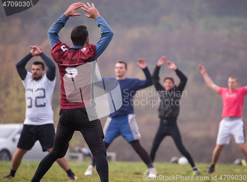 Image of american football players stretching and warming up