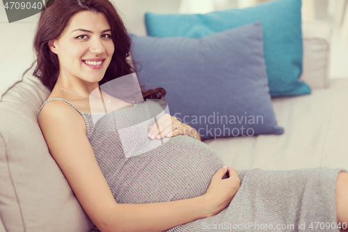 Image of pregnant woman sitting on sofa at home