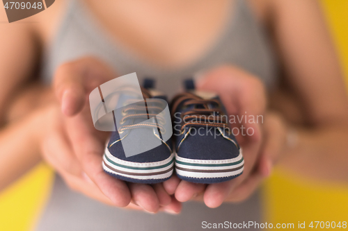 Image of couple holding newborn baby shoes