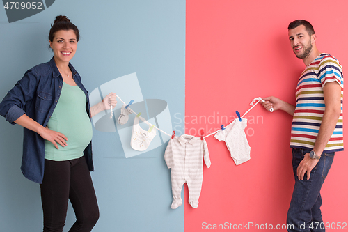 Image of young couple holding baby bodysuits