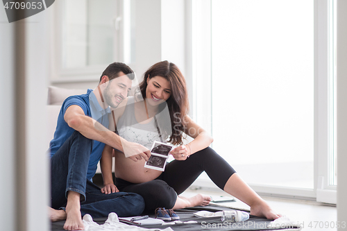 Image of pregnant couple checking a list of things for their unborn baby