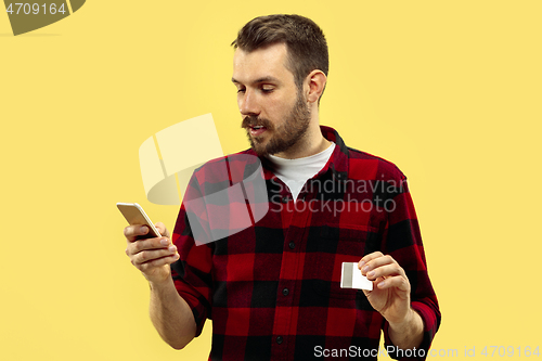 Image of Half-length close up portrait of young man on yellow background.