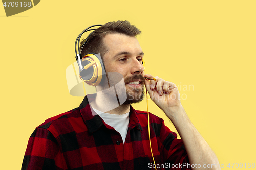 Image of Half-length close up portrait of young man on yellow background.