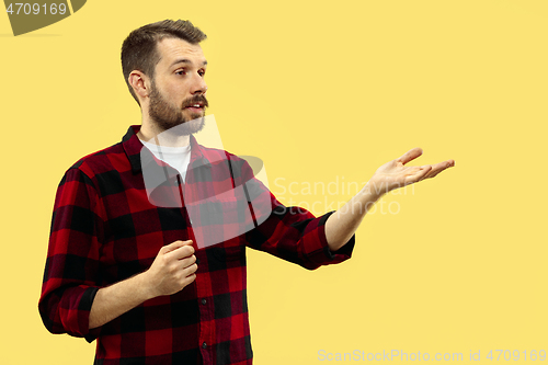 Image of Half-length close up portrait of young man on yellow background.