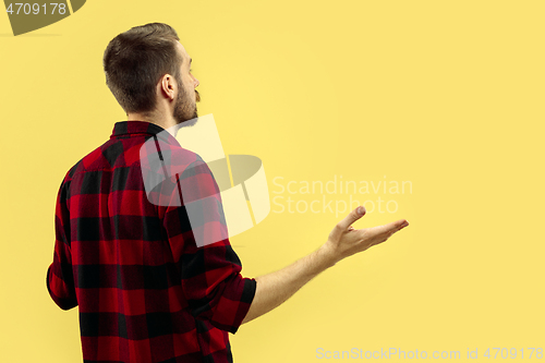 Image of Half-length close up portrait of young man on yellow background.