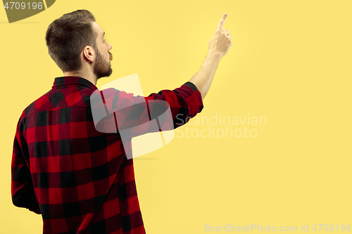 Image of Half-length close up portrait of young man on yellow background.