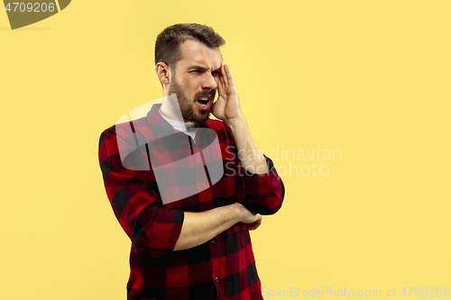 Image of Half-length close up portrait of young man on yellow background.